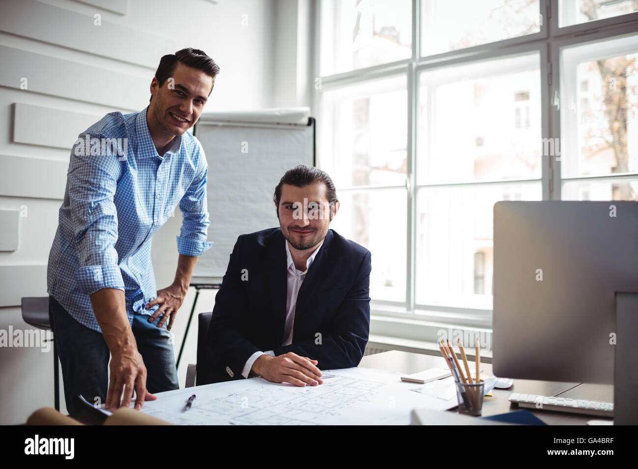smiling interior designer with coworker working on blueprint Stock Photo