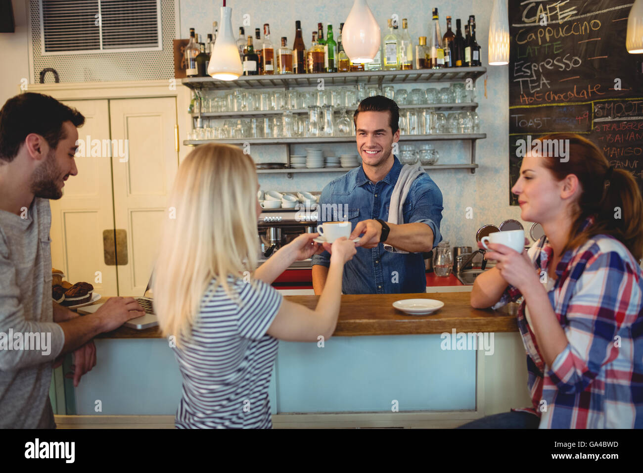 Handsome waiter serving coffee to customer with friends Stock Photo