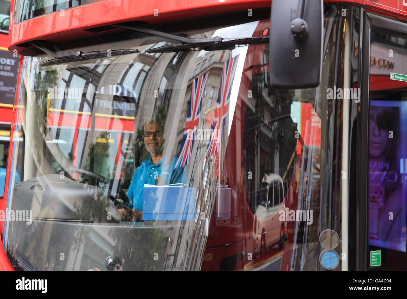 Union Jack flags reflected in a red London bus's window in the West End, on Oxford Street, in England, UK Stock Photo