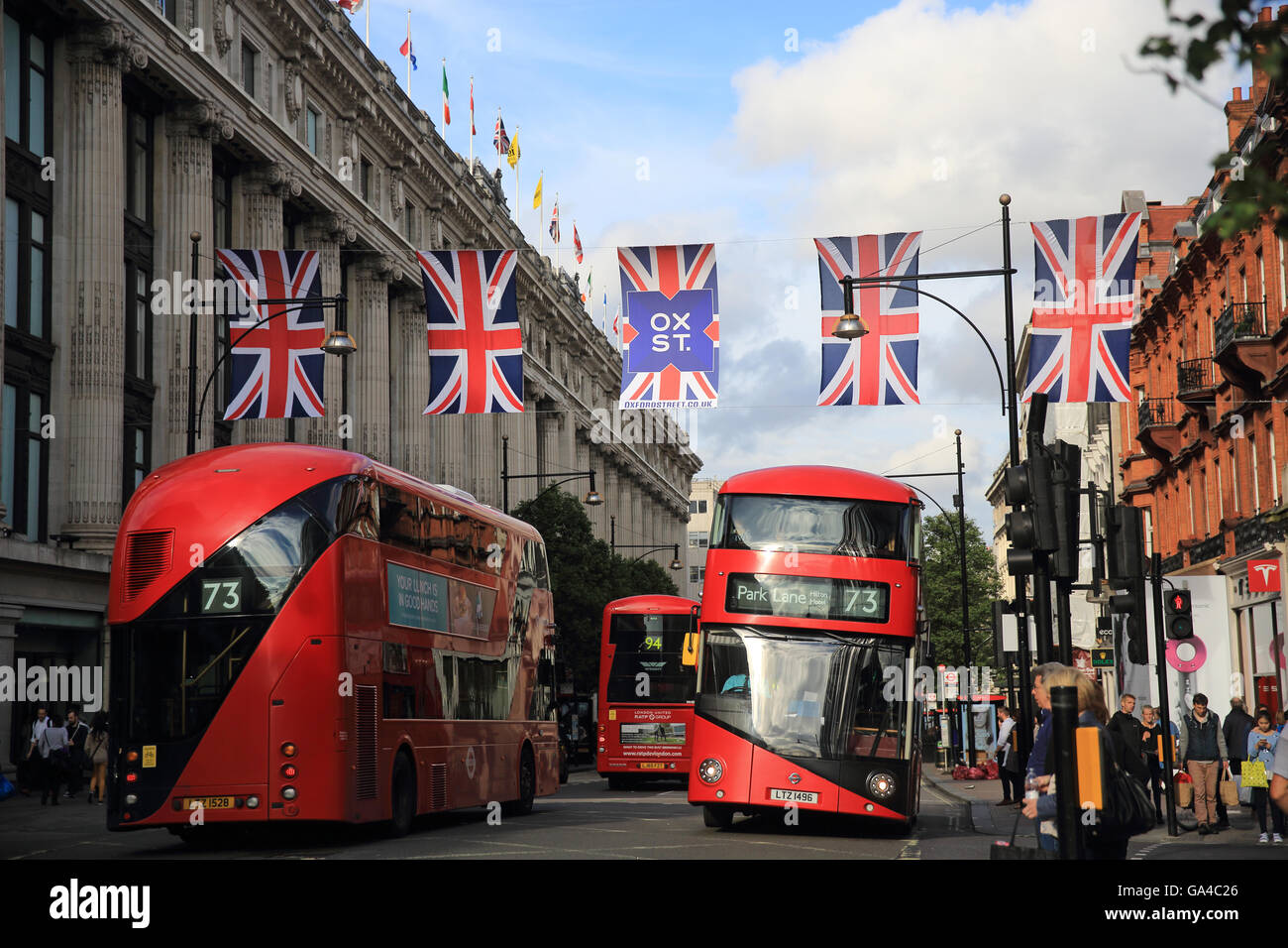 Union Jack flags and red buses line Oxford Street, next to Selfridges department store, in central London, England, UK Stock Photo