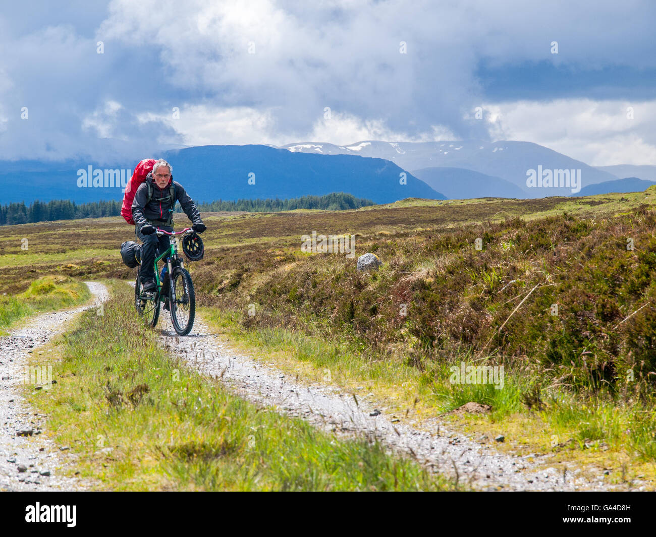 Retired man on a bike-packing ride through the Scottish Highlands Stock Photo