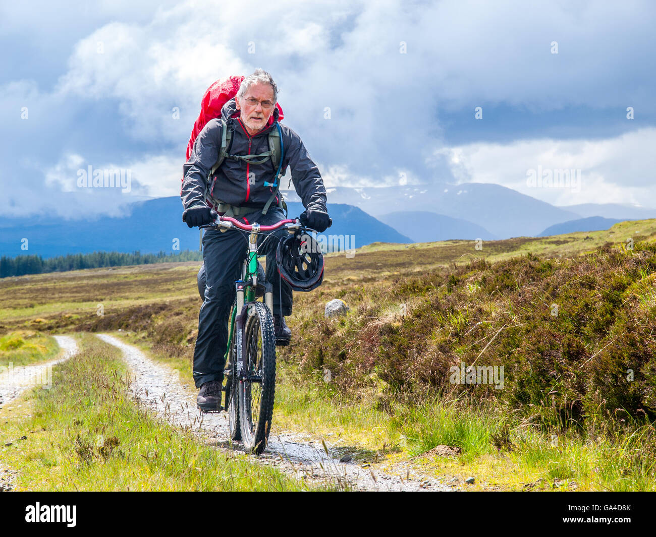 Retired man on a bike-packing ride through the Scottish Highlands Stock Photo