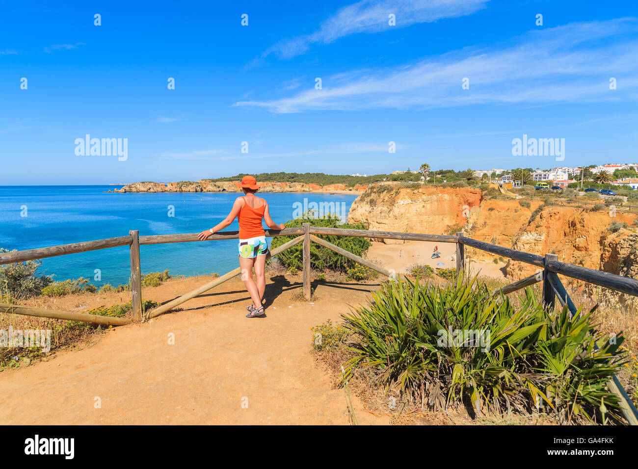 Young woman tourist standing on viewpoint and looking at beautiful Praia da Rocha beach, Portugal Stock Photo
