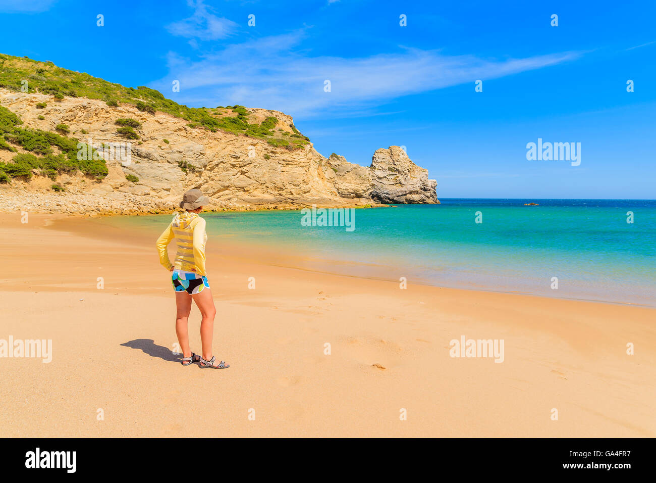 Young woman tourist standing on beautiful sandy beach in Algarve region, Portugal Stock Photo