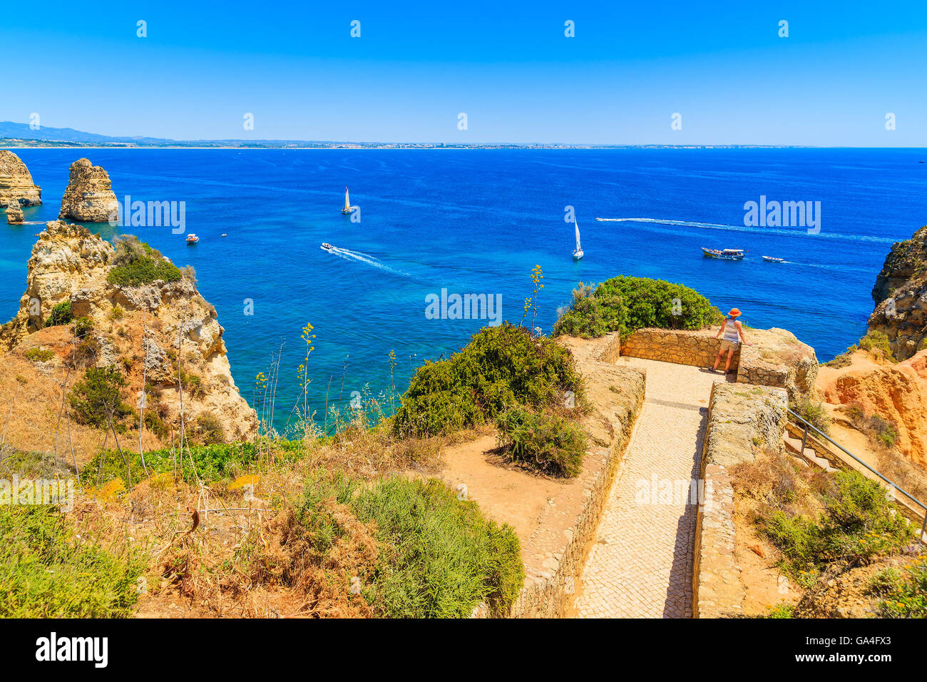 Young woman tourist standing on a viewpoint and looking at blue sea, Ponta da Piedade, Portugal Stock Photo