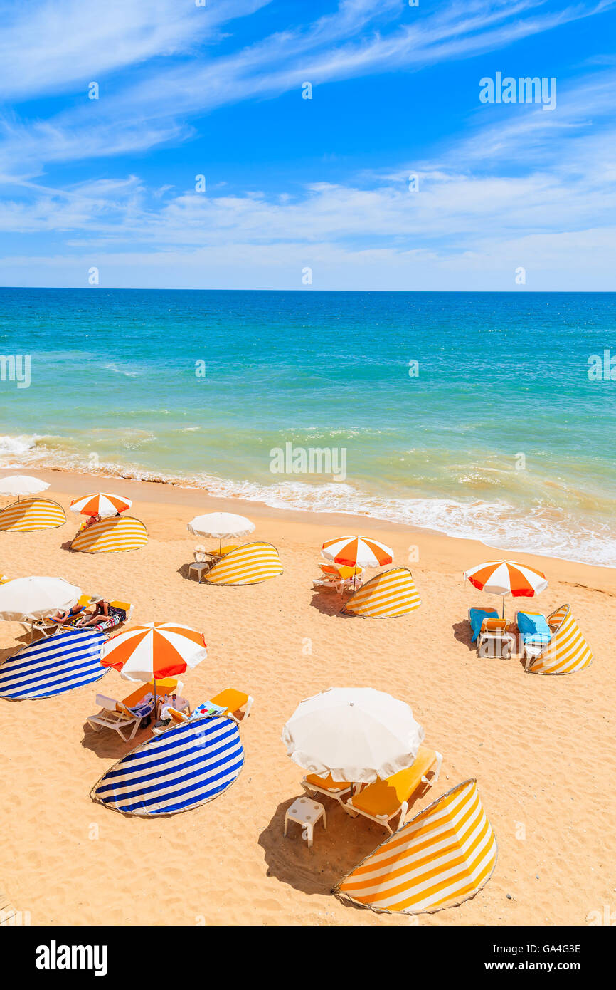 Sun umbrellas on idyllic beach in Armacao de Pera seaside town, Algarve region, Portugal Stock Photo