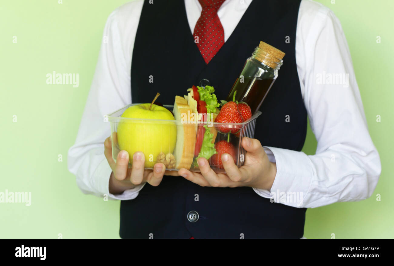 Boy in school uniform and lunch box with sandwich and fruits healthy