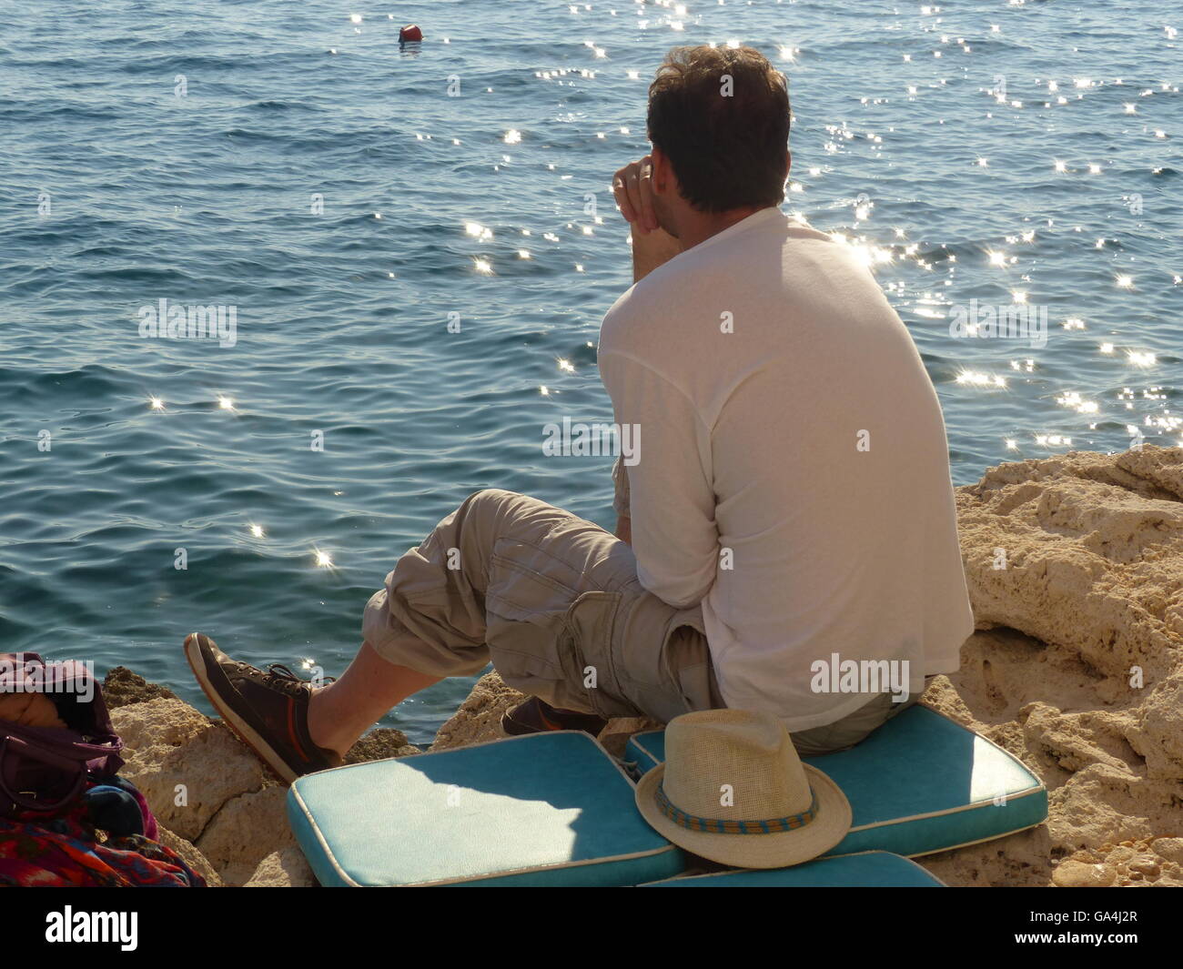 Young man sitting on the rocks hi-res stock photography and images - Alamy