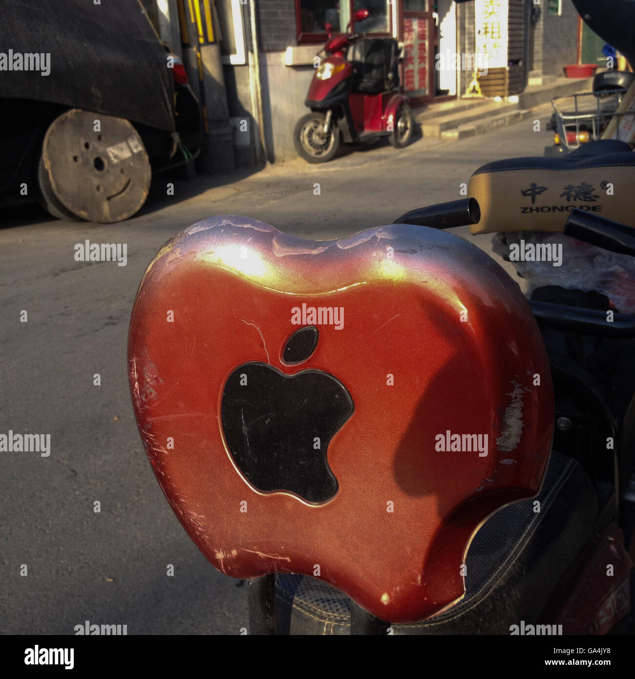 Apple Mac logo on back of a moped seat, in the Shitou and Dashilar hutong area, in Beijing, China. Stock Photo