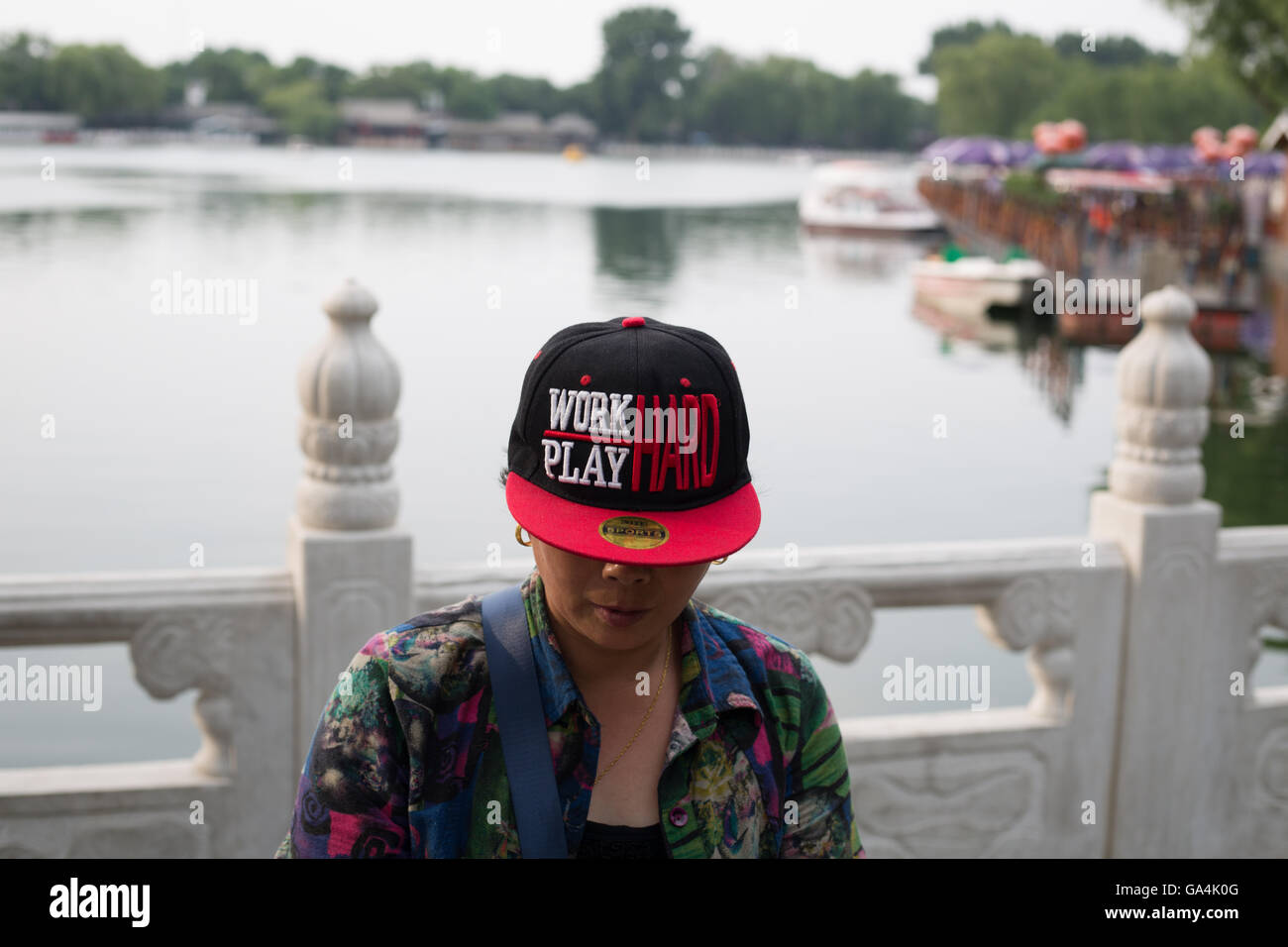 Woman wearing hat reading 'Work Hard, Play Hard', at Bei Hai and Hou Hai Lake area of Beijing, China. Stock Photo