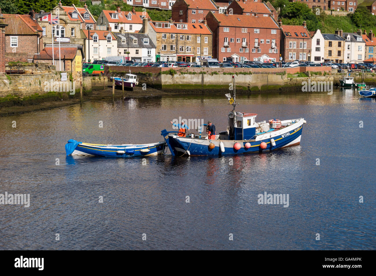 Two fishermen in their boat  WY144 'Jane Elizabeth' arriving in Whitby harbour towing a skiff Stock Photo