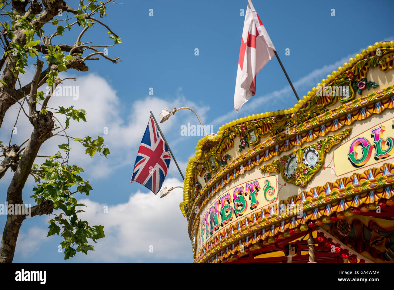Fairground carousel ride with Union Jack and St George cross flags flying from its rim Stock Photo