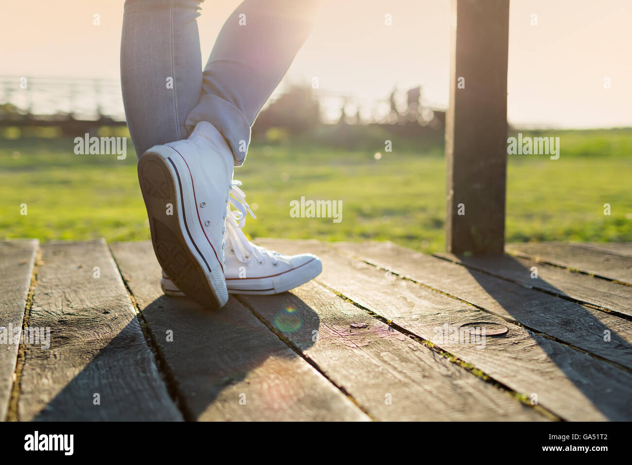 woman's legs in trainers against the sunset Stock Photo