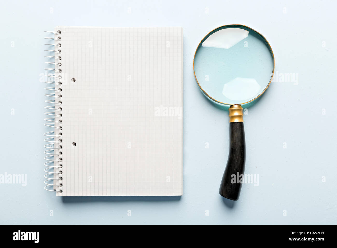 magnifier and notebook on blue background, flat lay Stock Photo