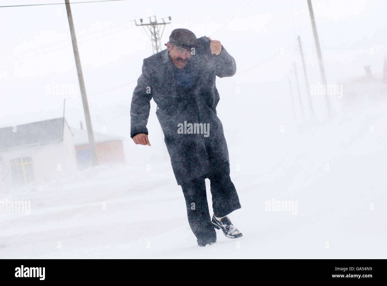 The man which is wearing black coat into blowing snow at Cildir