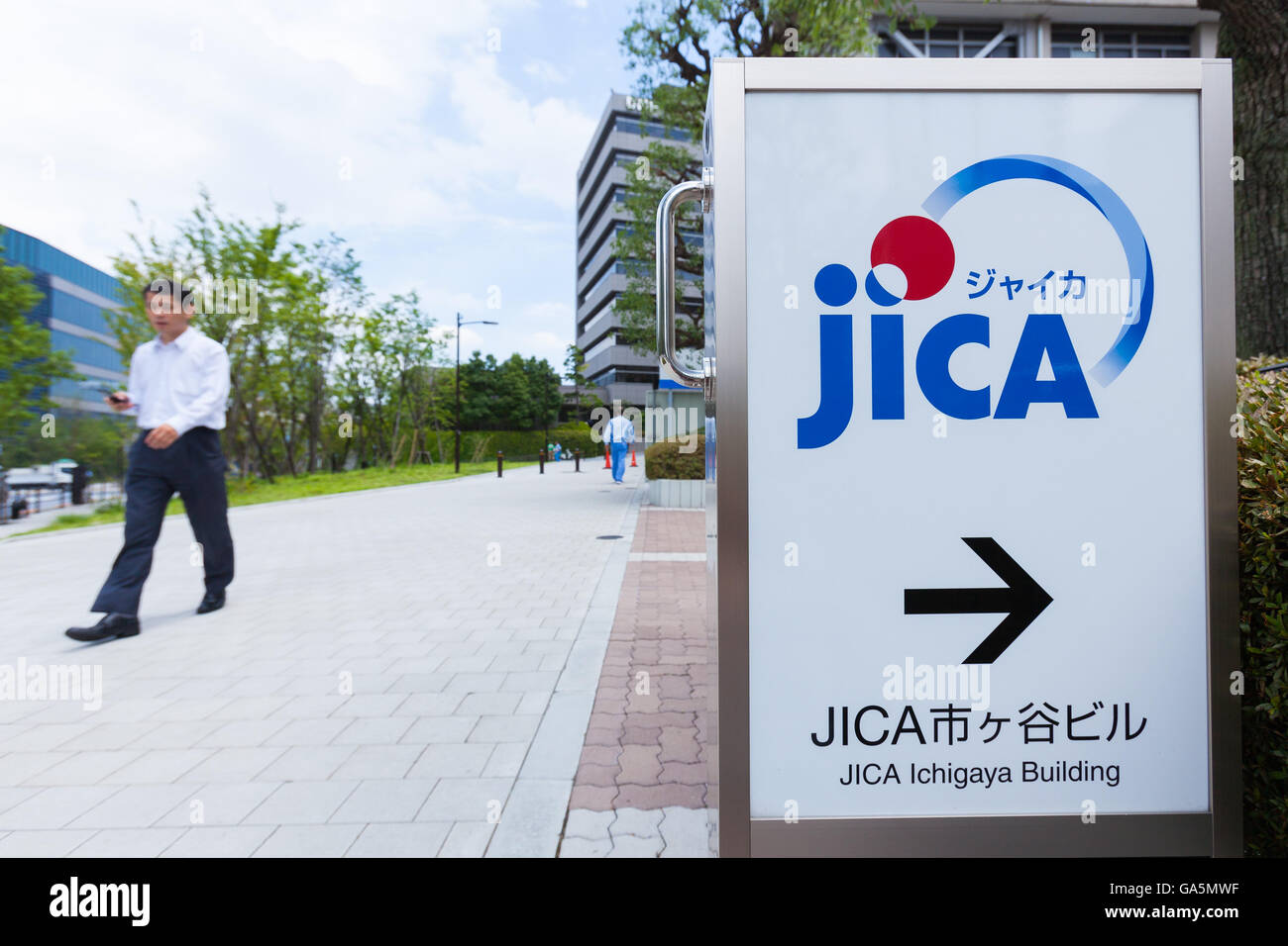 A man walks past a JICA signboard on display outside its Ichigaya building in Tokyo on July 4, 2016, Japan. Seven Japanese working on a transportation infrastructure project managed by the International Cooperation Agency (JICA) were among 28 who died in a terrorist attack on a cafe in Bangladesh's capital, Dhaka, on July 1st. The Japanese Prime Minister Shinzo Abe expressed his anger over the attack calling it an unforgivable act of terrorism and JICA's President Shinichi Kitaoka also expressed his grief after hearing that seven Japanese had been killed. (Photo by Rodrigo Reyes Marin/AFLO) Stock Photo