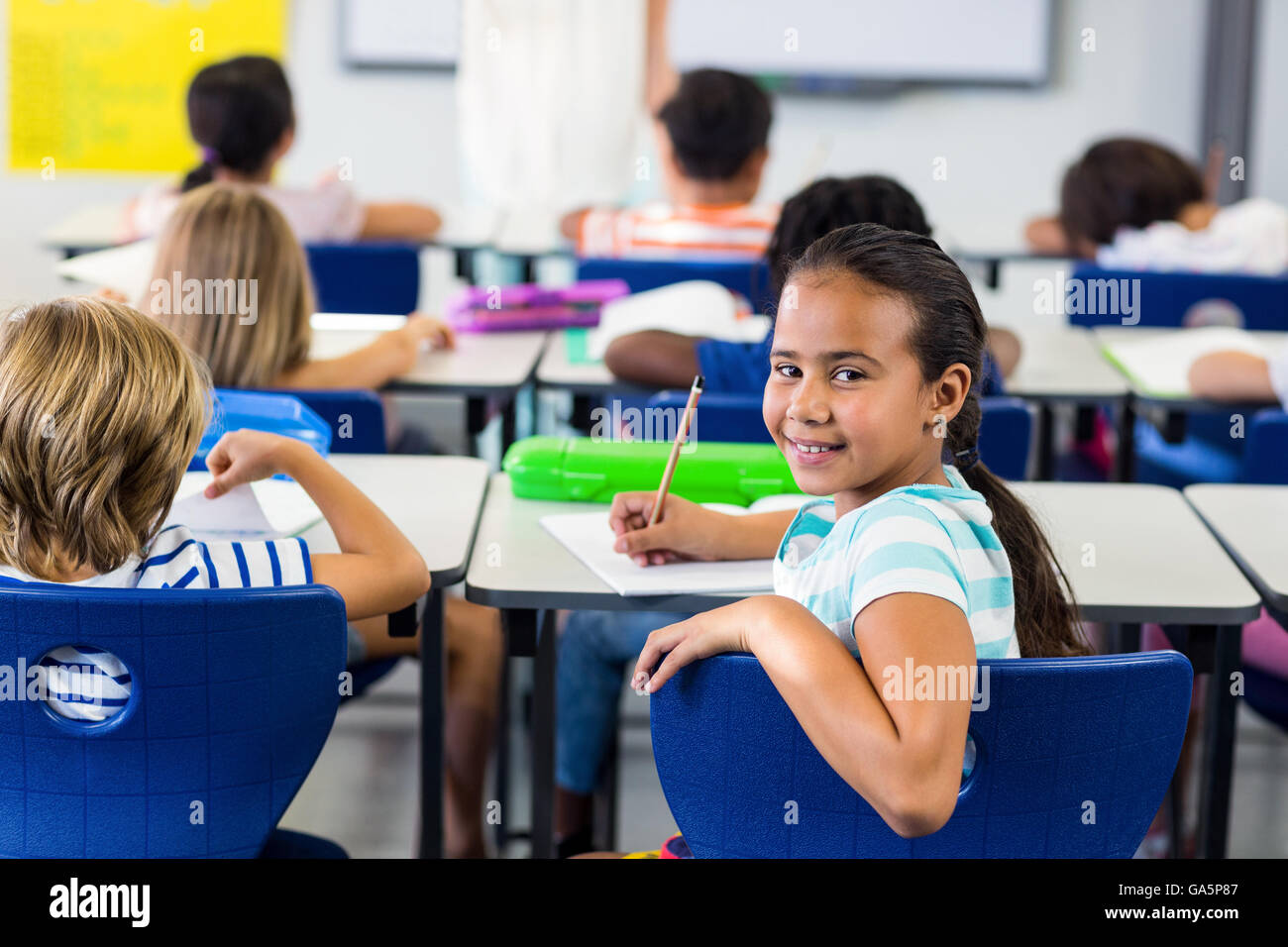 Girl with classmates in classroom Stock Photo