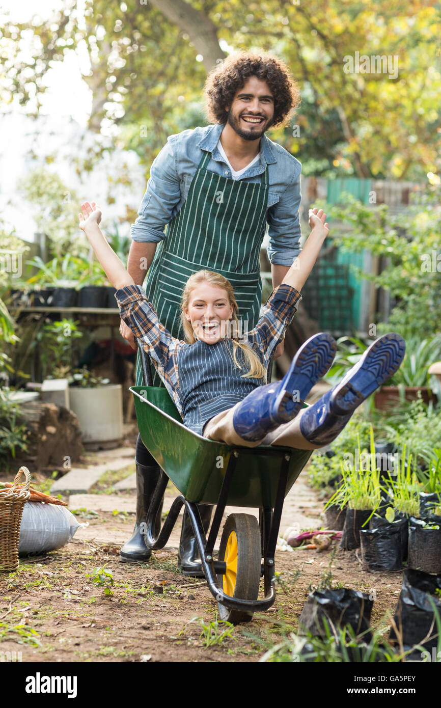 Cheerful man giving wheelbarrow ride to female gardener Stock Photo