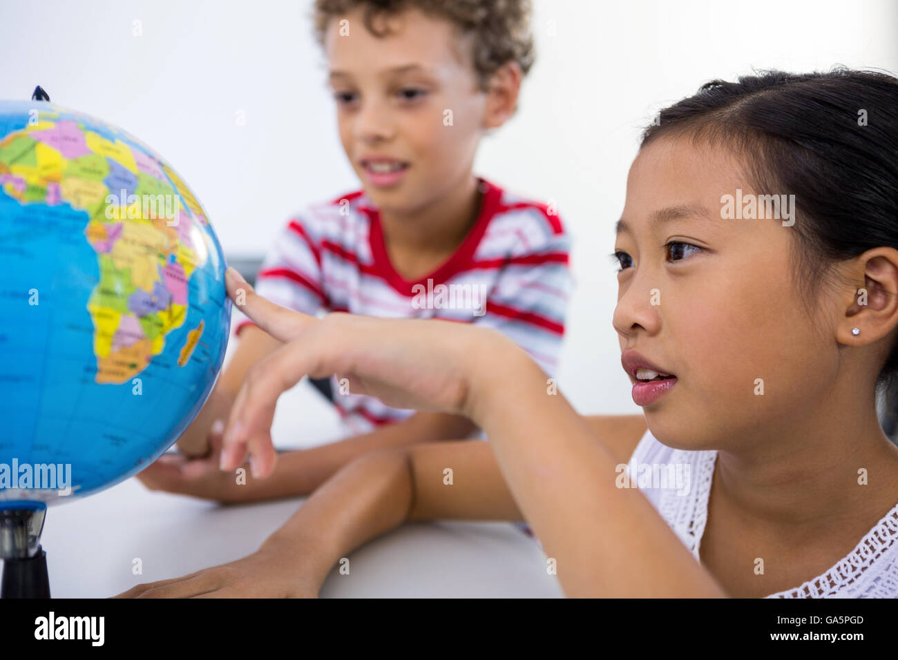 Boy and girl looking at glob in classroom Stock Photo