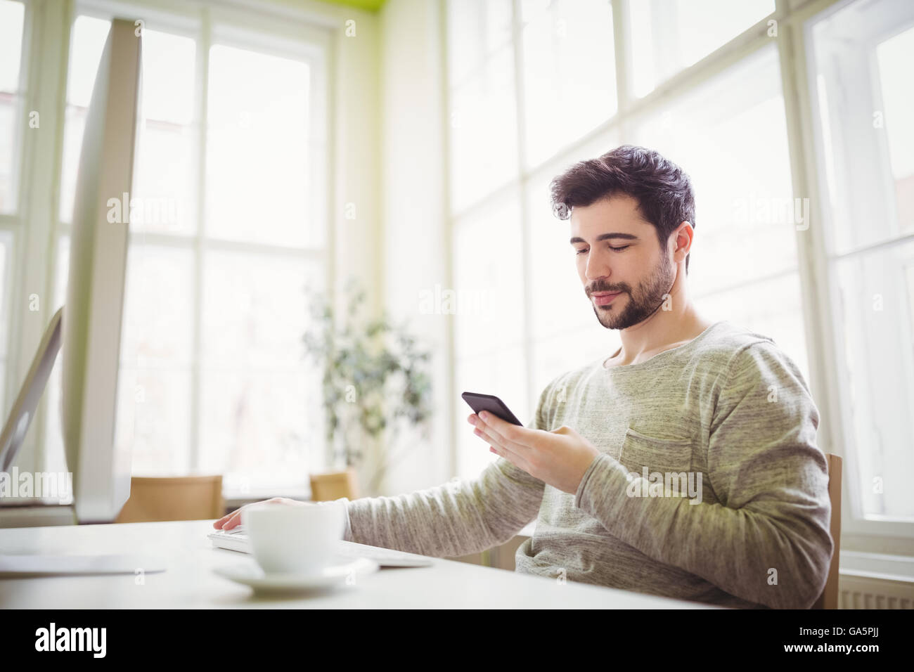 Businessman using mobile phone while working in office Stock Photo - Alamy