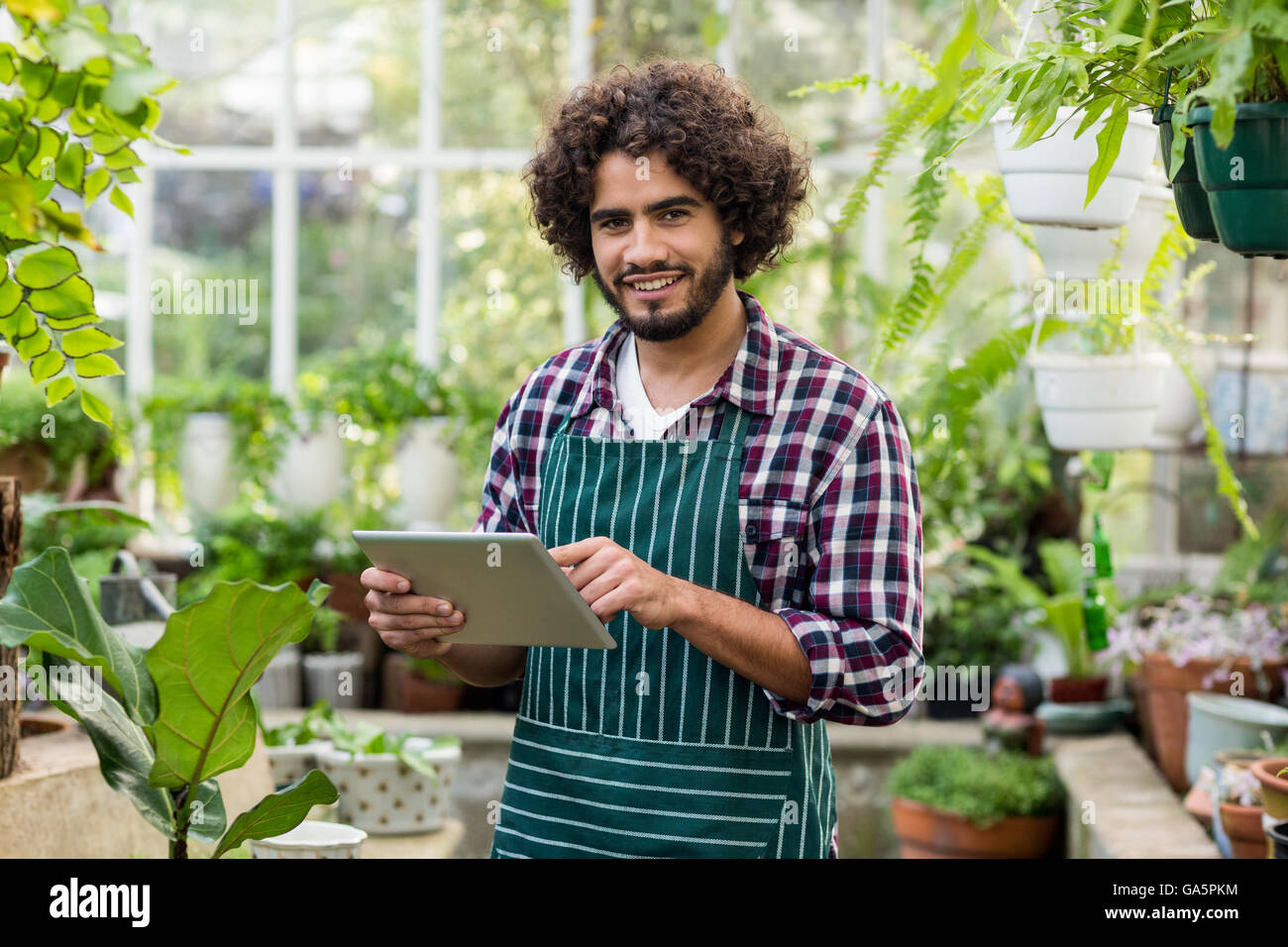 Male gardener using digital tablet at greenhouse Stock Photo