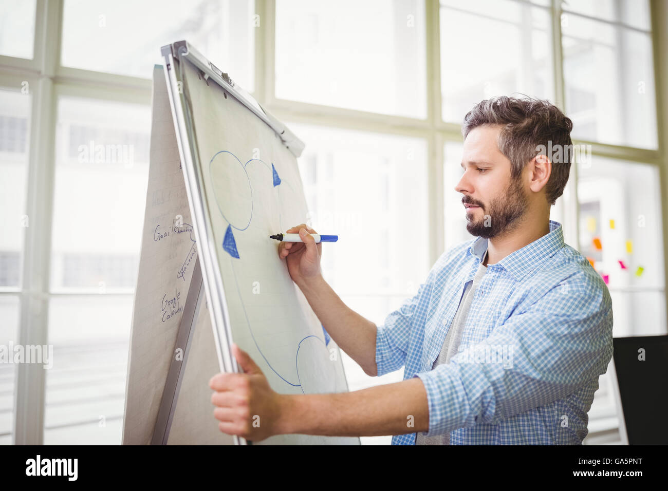 Businessman drawing diagram on whiteboard in creative office Stock Photo