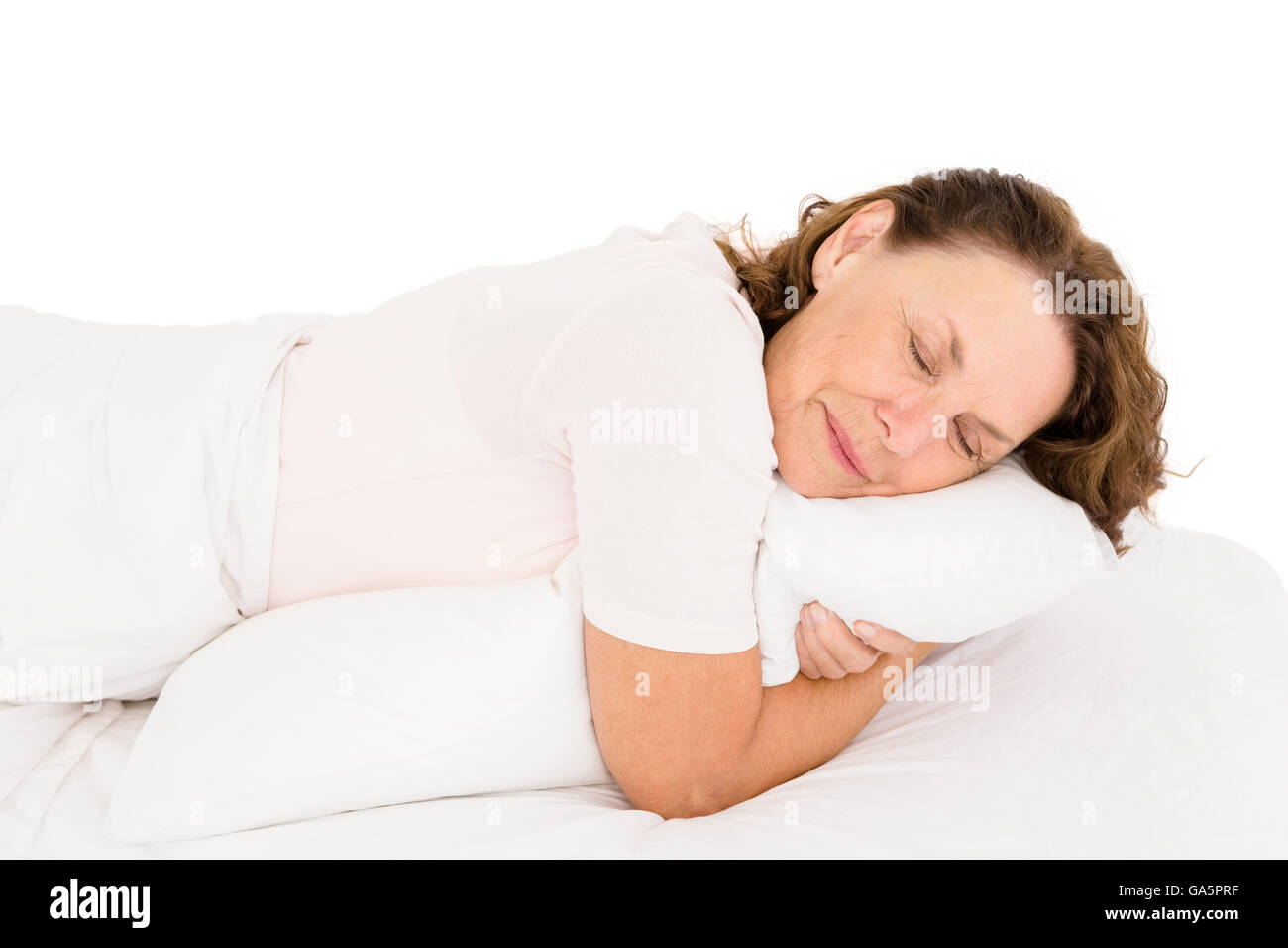 Mature woman hugging pillow while sleeping on bed Stock Photo