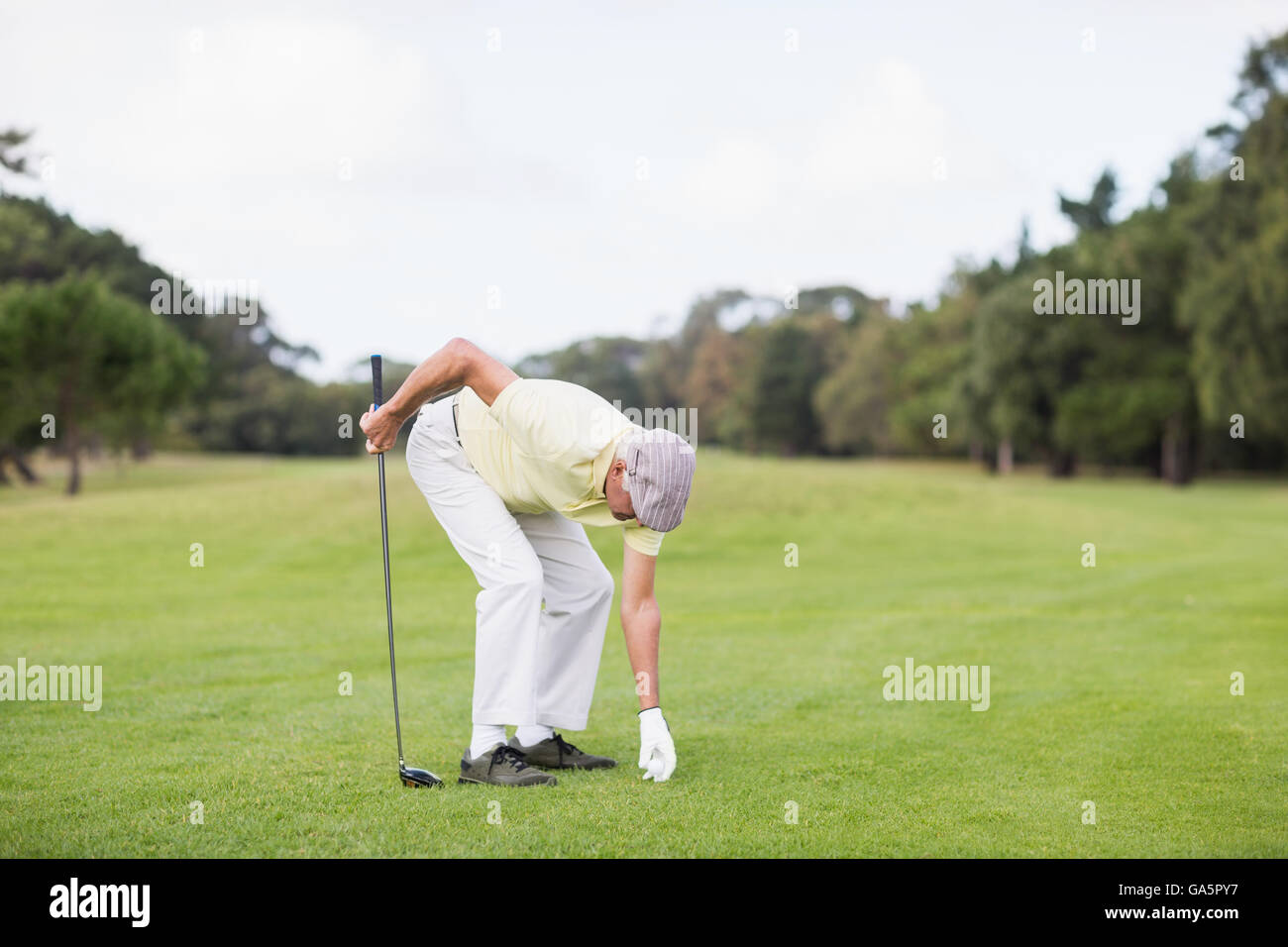 Mature man holding golf club while bending Stock Photo Alamy