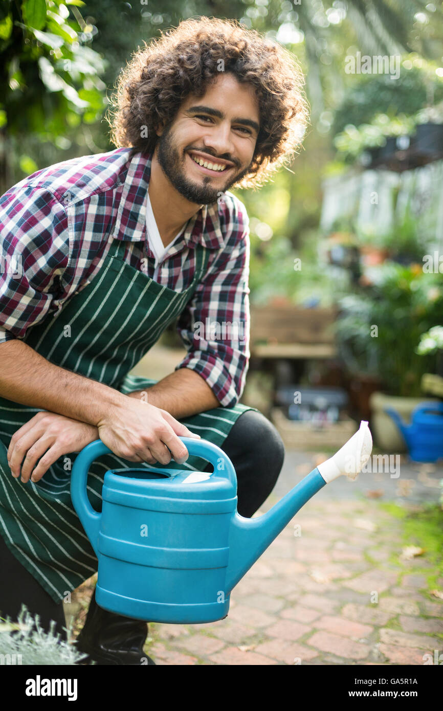 Male gardener with watering can at greenhouse Stock Photo
