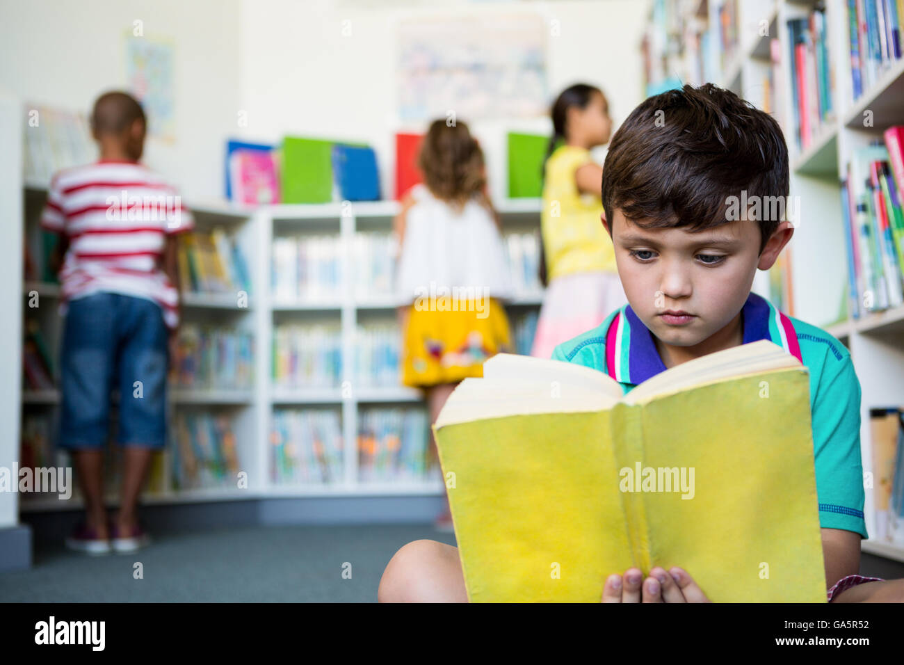 Elementary boy reading book at school library Stock Photo