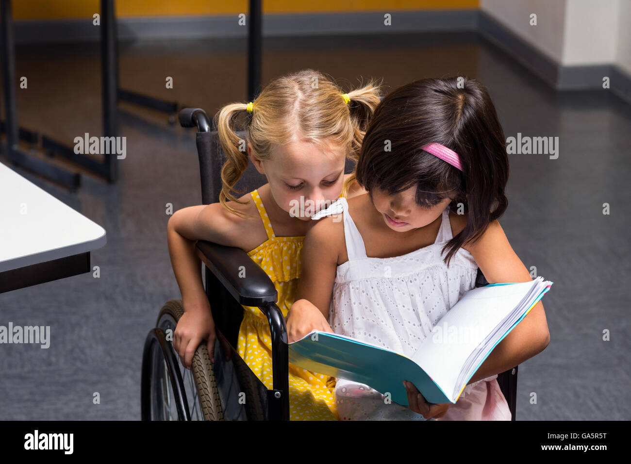 Girls sitting on wheelchair reading book Stock Photo