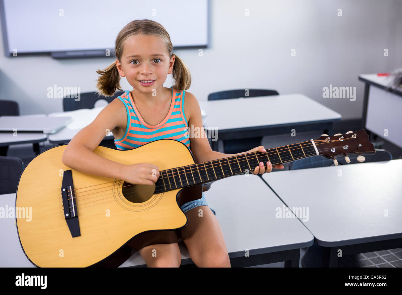 Portrait of happy girl playing guitar in classroom Stock Photo Alamy