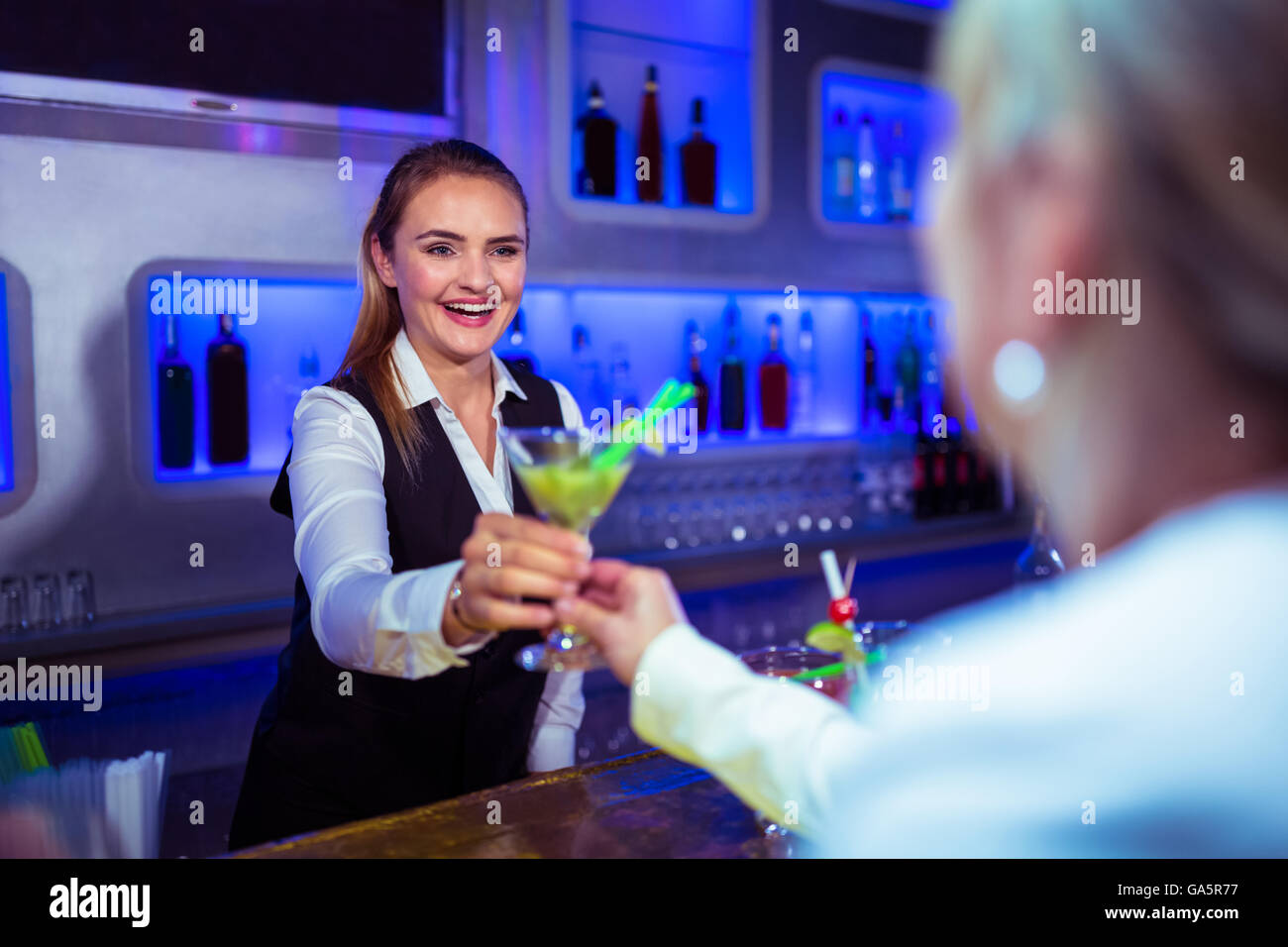 Beautiful bartender serving cocktail to woman Stock Photo