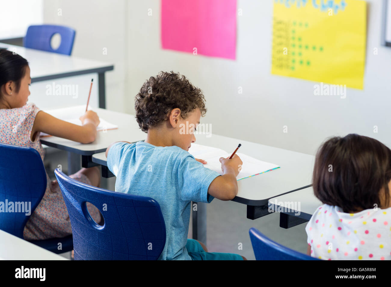 Schoolchildren writing on book in classroom Stock Photo