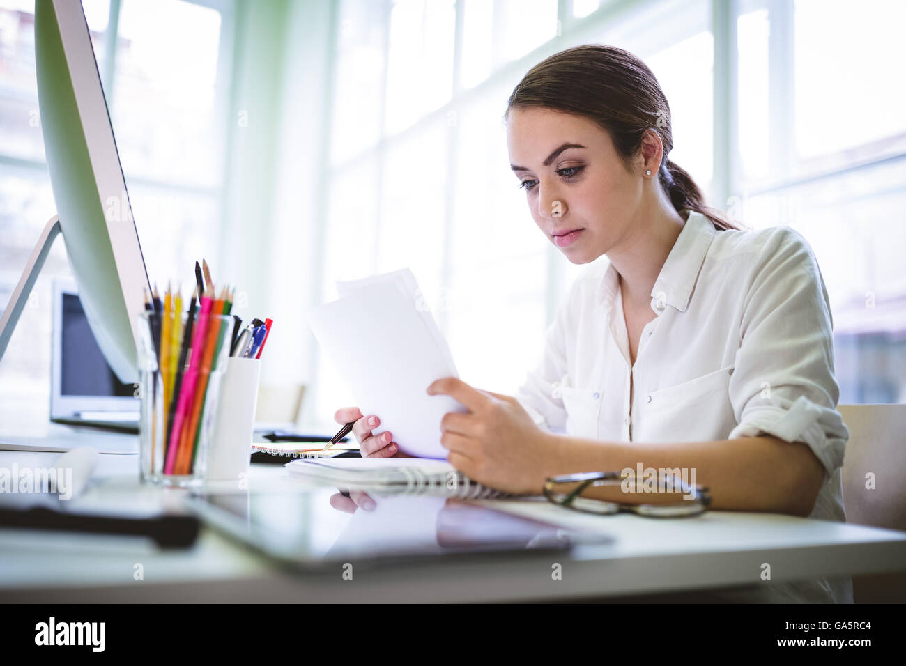Serious graphic designer writing on document Stock Photo - Alamy