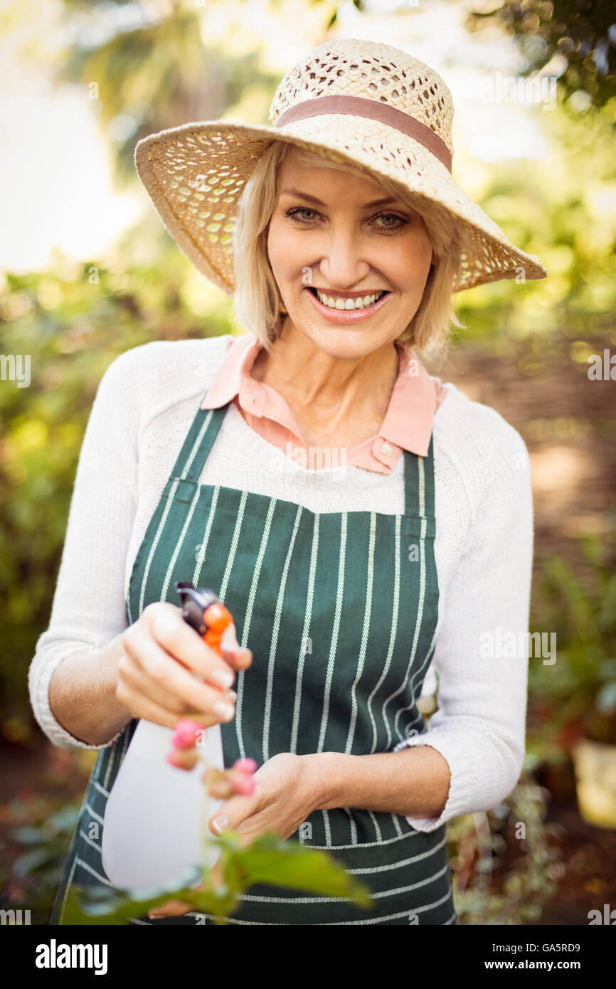 Woman smiling while watering plants Stock Photo - Alamy