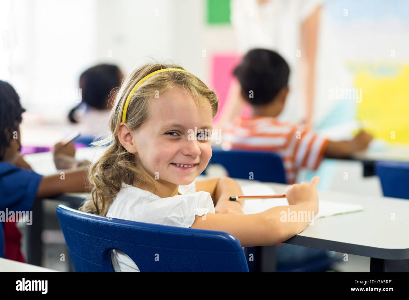 Cute girl with classmates in classroom Stock Photo