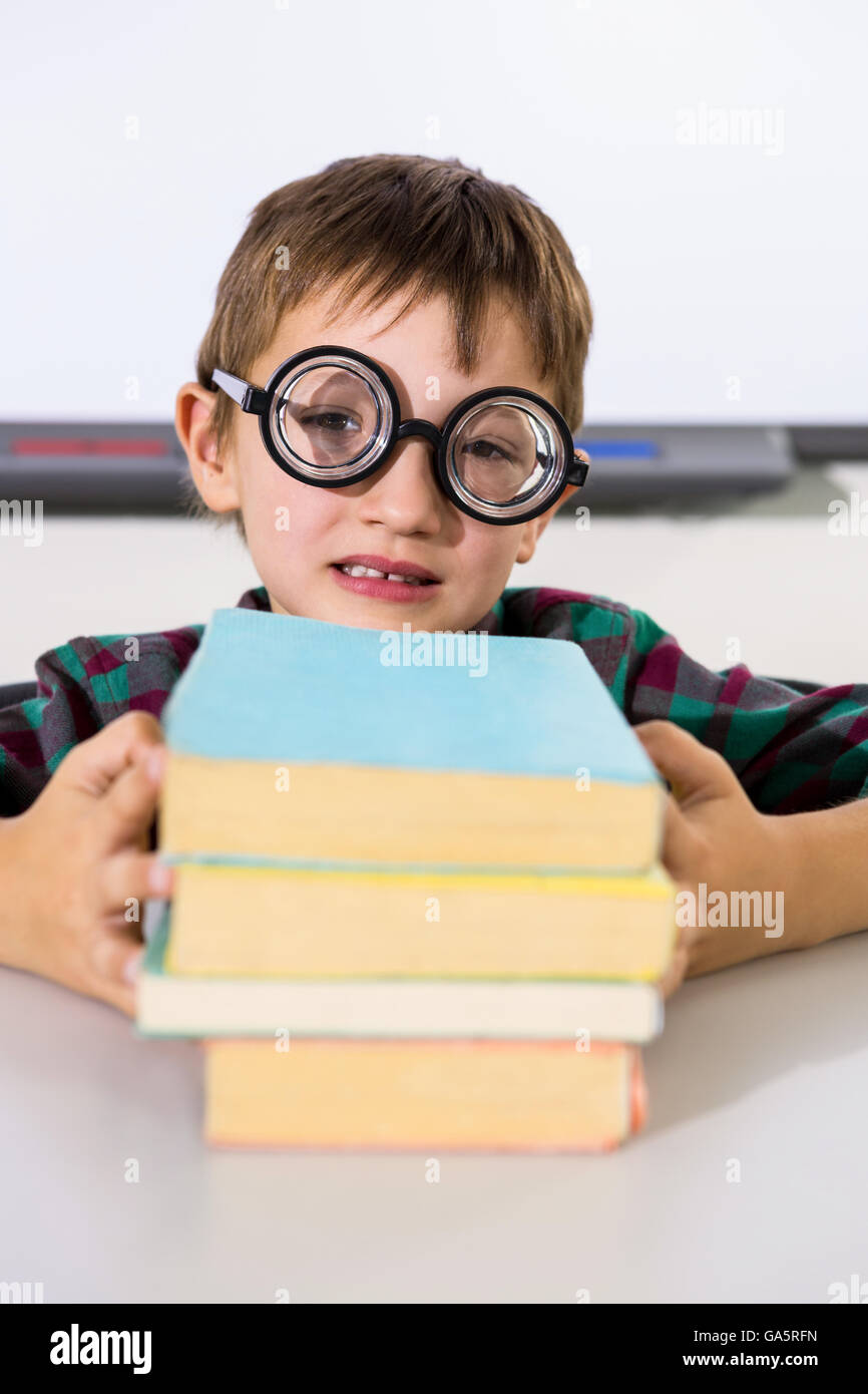 Boy holding books on table in classroom Stock Photo