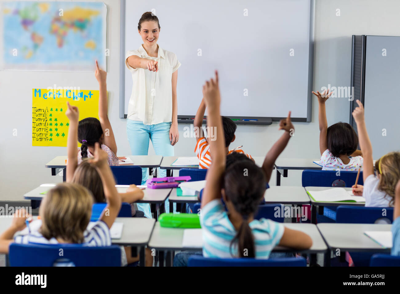 Teacher pointing students with raised hands Stock Photo