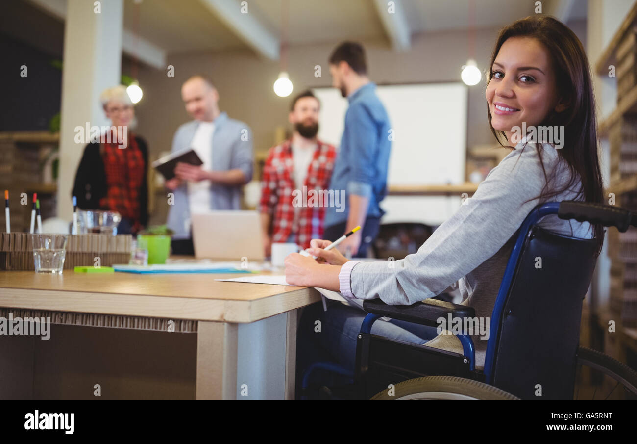 Confident disabled businesswoman writing at desk Stock Photo