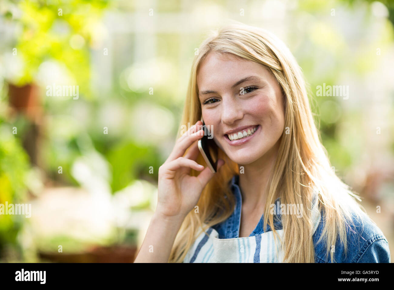 Young woman using cellphone at greenhouse Stock Photo