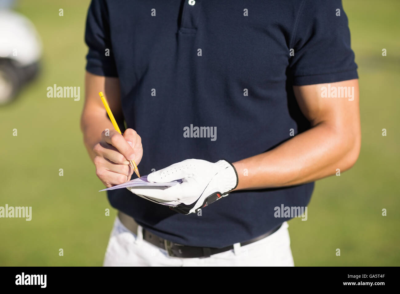 Midsection of golfer writing on score card Stock Photo