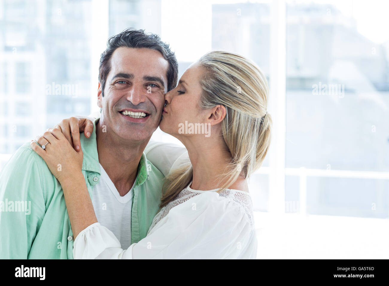 Mid adult woman kissing man at home Stock Photo