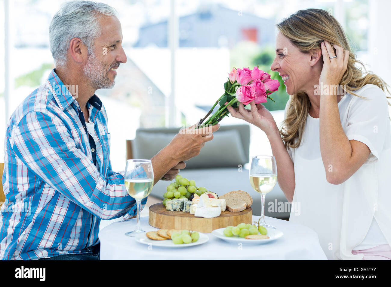Man giving pink roses to wife in restaurant Stock Photo