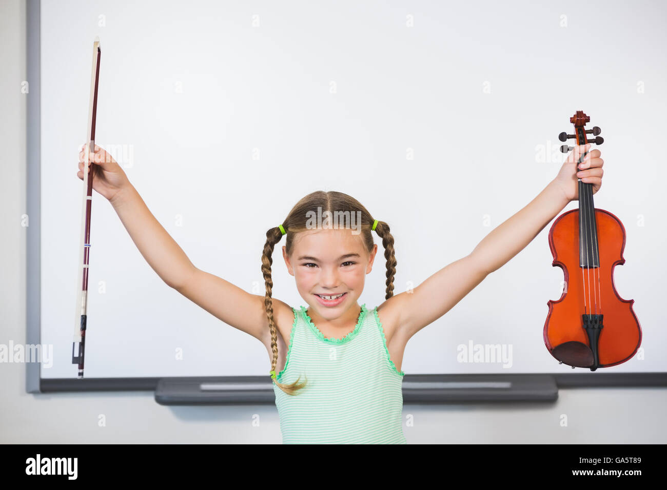 Portrait of smiling schoolgirl holding violin in classroom Stock Photo ...