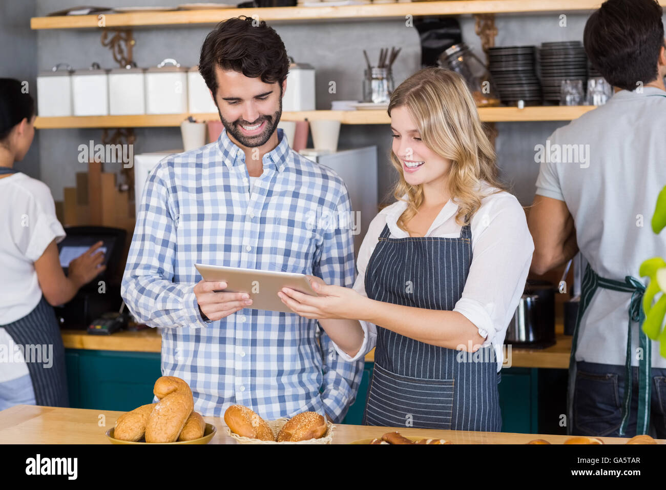 Man and waitress standing at counter using digital tablet Stock Photo