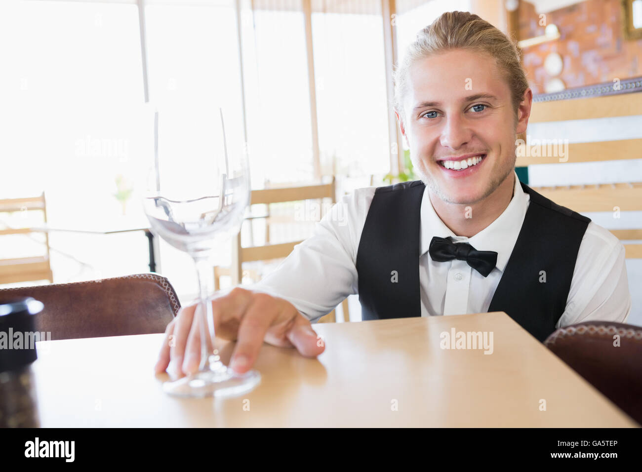 Waiter sitting at table with empty glass Stock Photo
