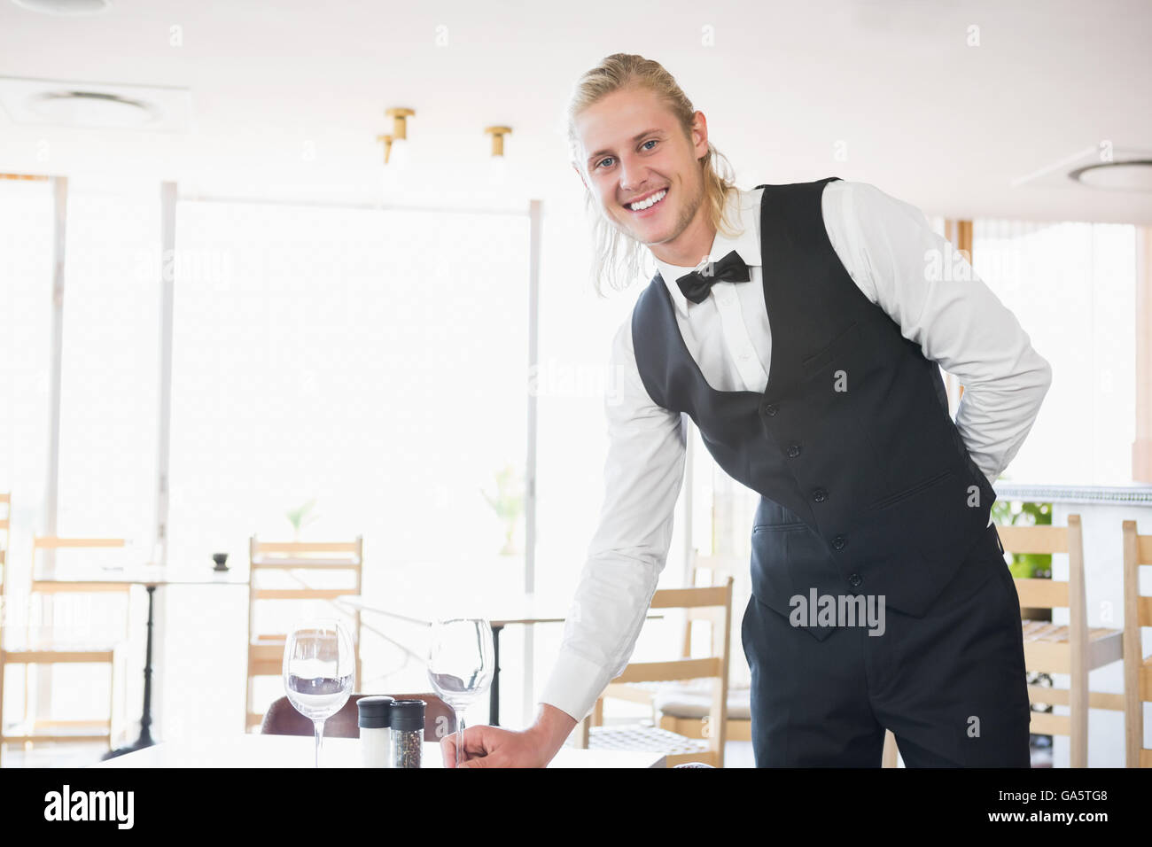 Waiter standing at table with empty glass Stock Photo