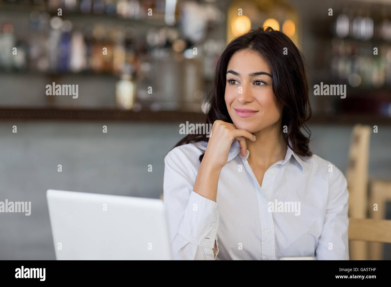 Thoughtful businesswoman sitting on table with laptop Stock Photo