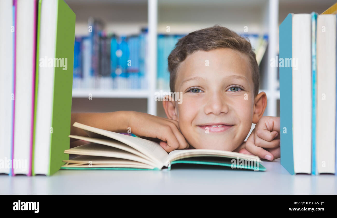 Schoolboy sitting on table and reading book in library Stock Photo
